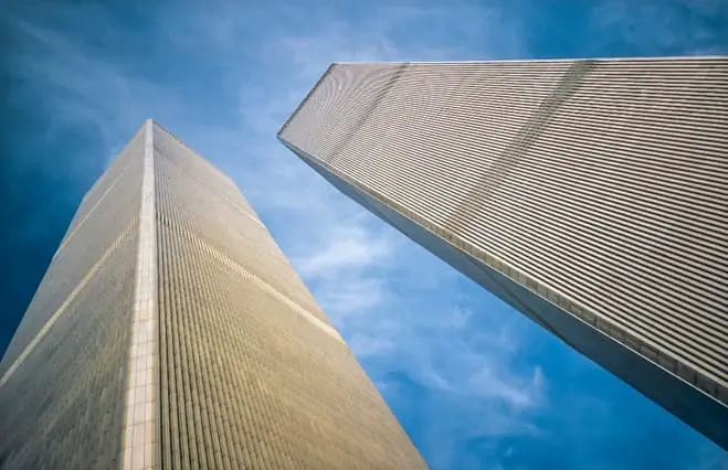 A skyward view of the World Trade Center’s Twin Towers with a blue sky behind them.