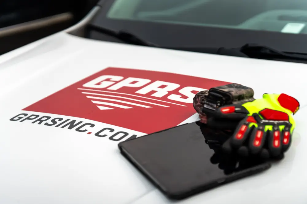 A GPR scanner, gloves, and tablet sitting on a GPRS-branded truck hood.