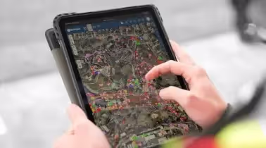 A mobile device displaying a SiteMap utility map, being held by a worker.
