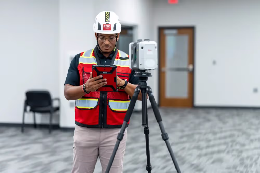 A GPRS Project Manager operating a 3D laser scanner while holding a tablet.