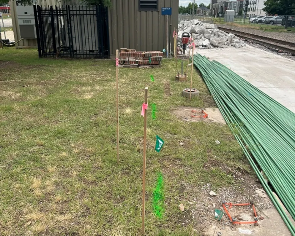 Green spray paint on a grassy area next to cement and train tracks