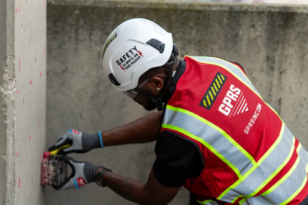 A GPRS Project Manager using a ground penetrating radar scanner to locate obstructions embedded in a concrete pillar.