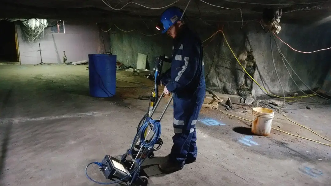 A worker conducts a GPR scan on a concrete pad in a mine shaft