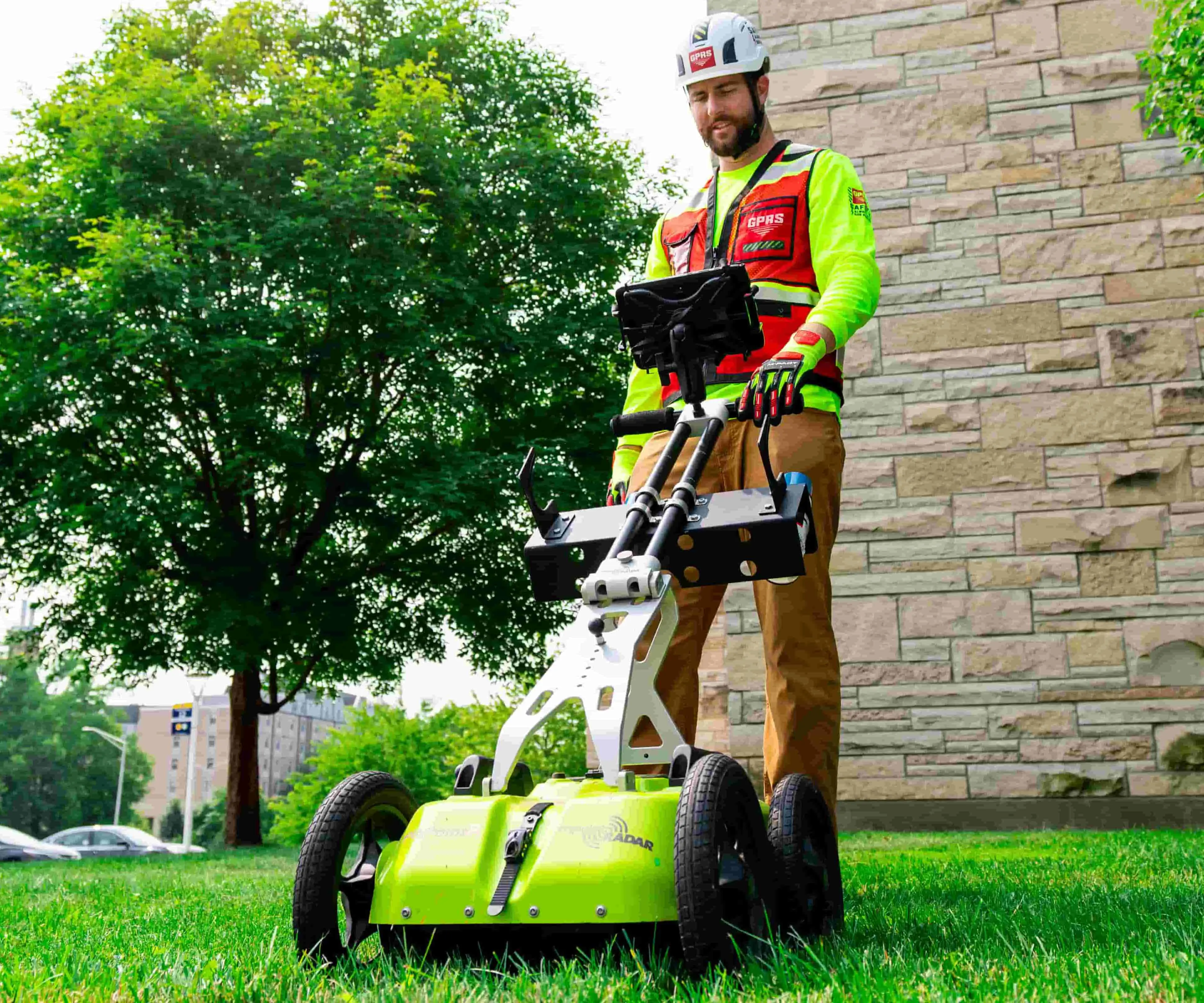 A worker conducts a utility locate next to a building.