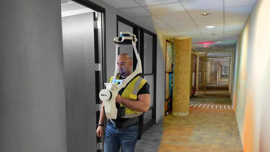 GPRS Project Manager utilizing a SLAM-based 3D laser scanner in a hallway. The Project Manager is wearing a yellow high-visibility vest. ¾ of the image has a black and white background, and the remainder showcases 3D point cloud data in color.