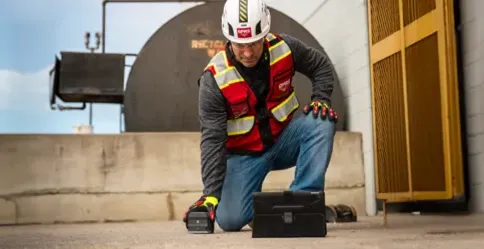 A GPRS Project Manager on one knee utilizing handheld ground penetrating radar to investigate what lies within and beneath a concrete slab.
