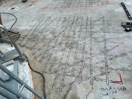 A concrete slab with black diagonal spray painted lines that represent rebar.