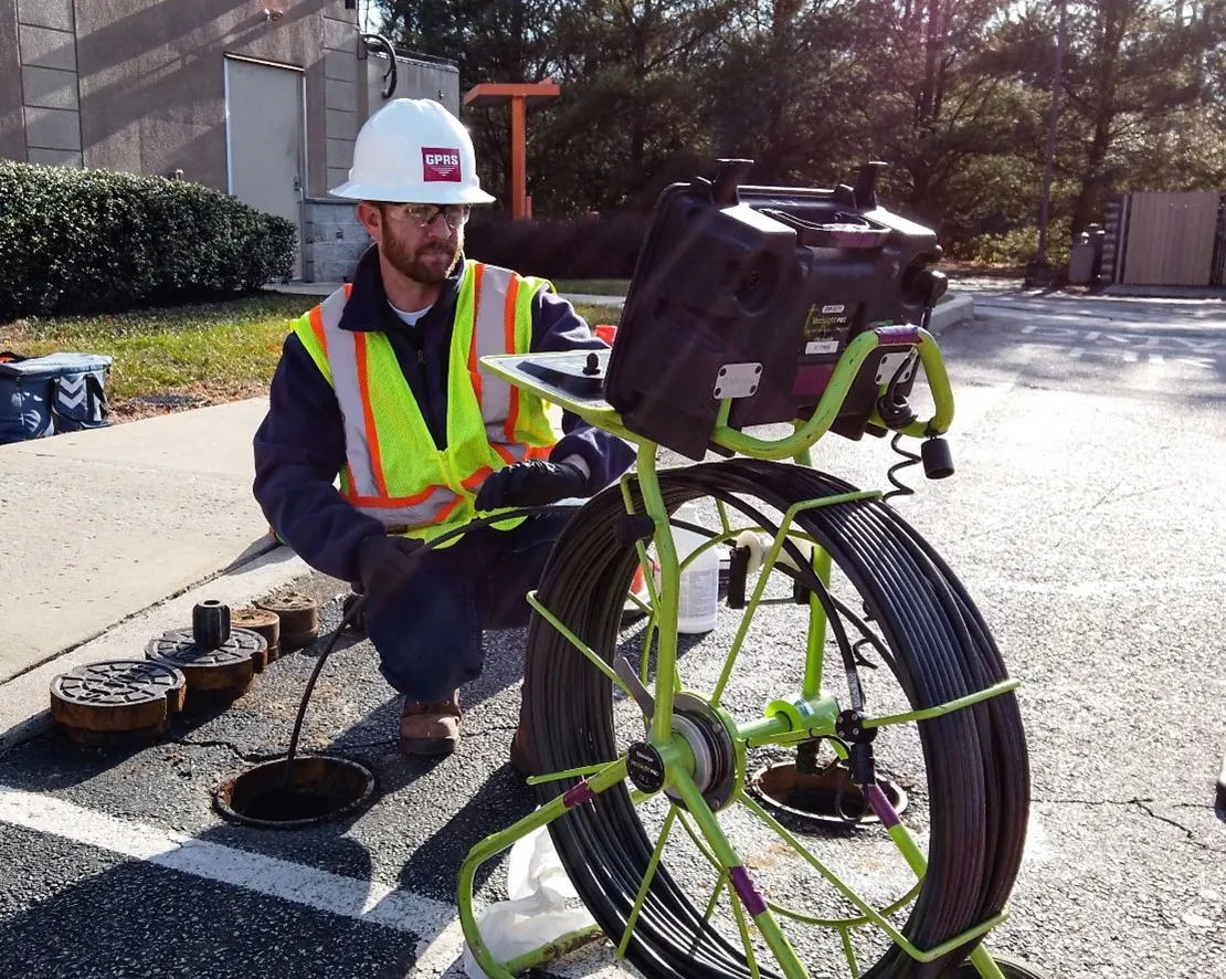 A GPRS Project Manager wearing a helmet and bright yellow vest while analyzing the results of a push camera in use.