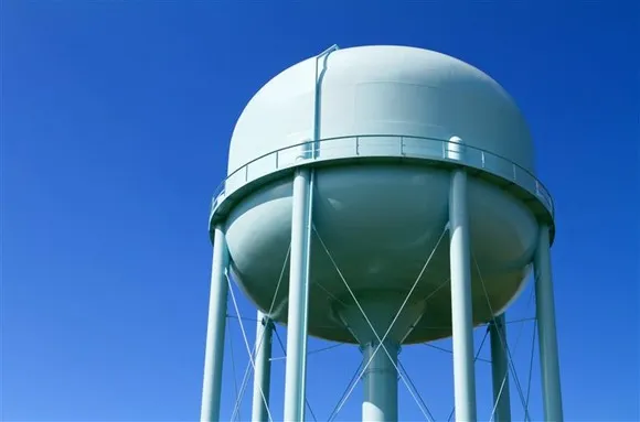 A light blue municipal water tower with a clear blue sky behind it.