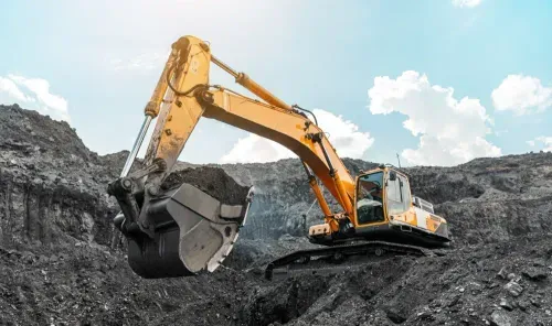 An excavators on a dark dirt job site after scooping dirt into the bucket.