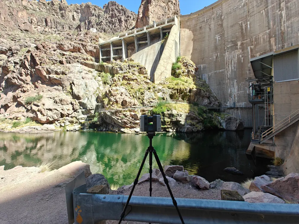 A 3D laser scanner on its tripod next to a hydroelectric dam.