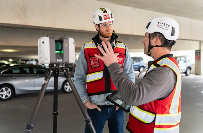 GPRS Project Managers wearing safety vests and helmets, 3D laser scanning in a parking garage.