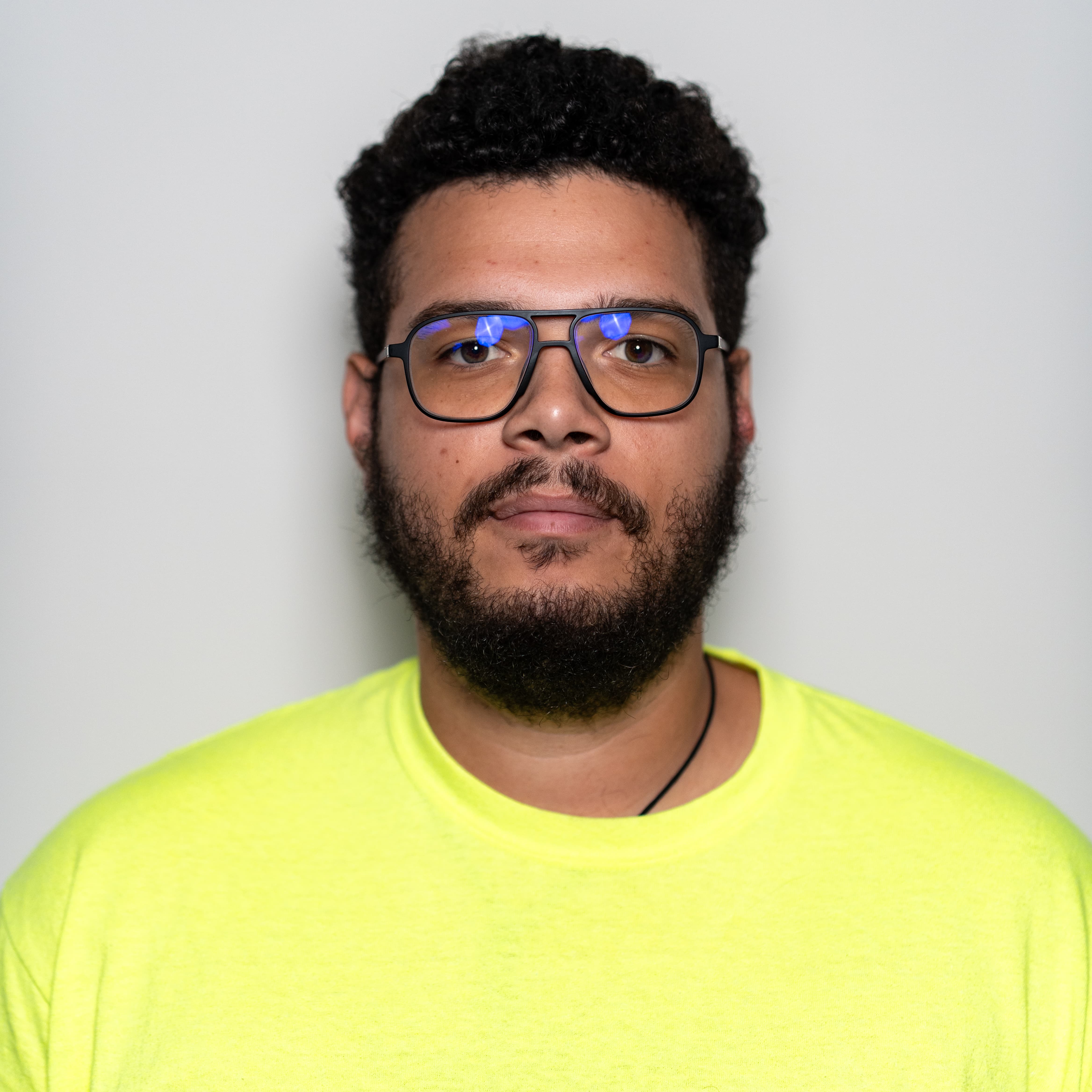 GPRS Project Manager Christopher Frias, a man with dark hair, a beard, and glasses, wearing a yellow safety shirt.