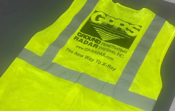 A yellow and grey high-visibility vest with the GPRS logo and the test “GROUND PENETRATING RADAR SYSTEMS INC.” “www.GP-RADAR.com” “The New Way To X-Ray,” Below the logo on the vest.