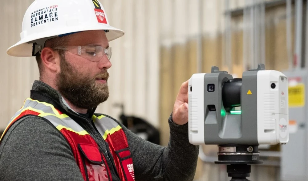 A man wearing a hard hat and safety vest is holding a device. - GPRS Images
