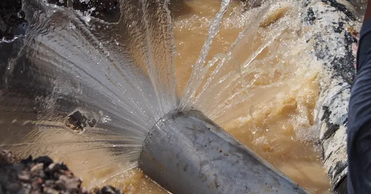 A metal pipe in the ground leaking water