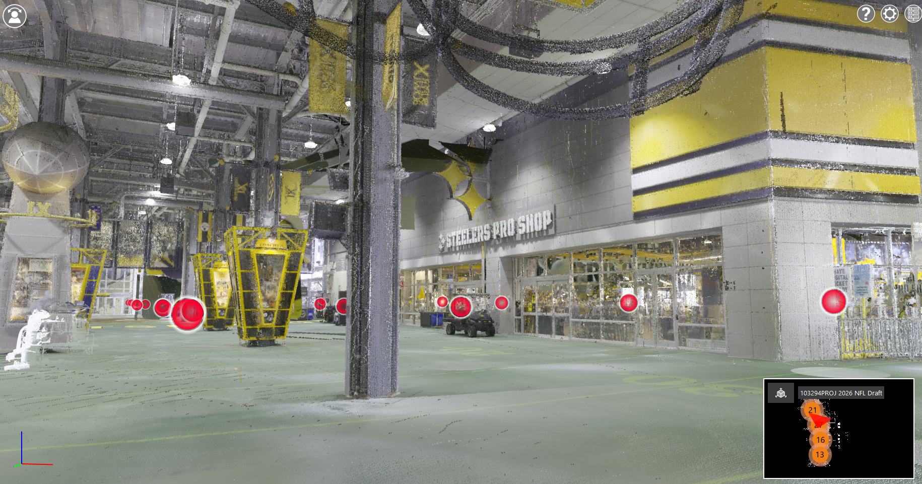 Interior of a large industrial-style sports venue or stadium concourse shown as a detailed 3D scan, with concrete floors, exposed ceiling beams, hanging cables, and yellow structural accents. A gray support column stands in the foreground. In the background, glass storefront windows display a sign reading “Steelers Pro Shop.” Yellow metal frameworks and equipment are scattered across the open space. Several red circular markers appear throughout the scene, suggesting scanned reference points or annotations. Lighting is bright and even, with gray, yellow, and metallic tones dominating the environment.