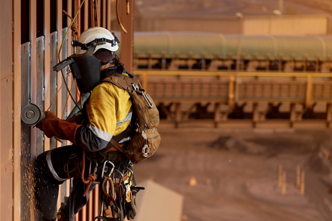 A construction worker uses high-viz clothing, PPE, and fall protection to work safely at a high altitude.