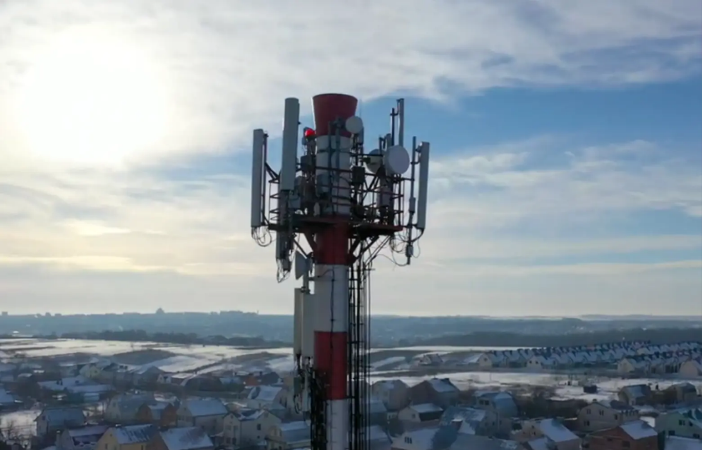 Telecom cell tower with mounted antennas overlooking a residential area to support wireless network infrastructure expansion.