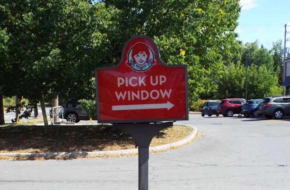 A national QSR chain's "classic" pick up window signage, directing drivers through the parking lot to the drive-thru