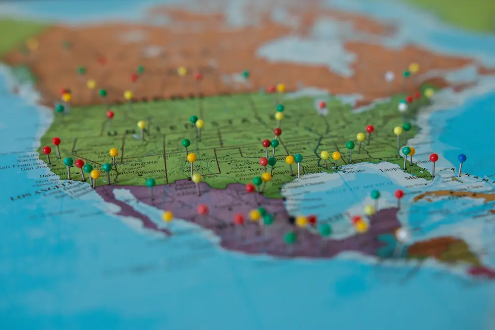 Red, green, yellow and blue push pins decorate a colorful map of U.S., Canada and Mexico. 