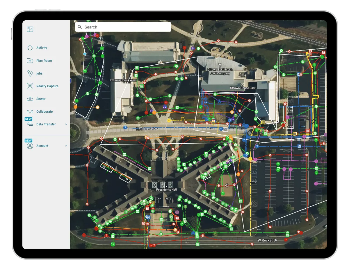 A tablet screen displaying a detailed aerial map of a campus‑style facility with multicolored utility lines, symbols, and pathways overlaid. A navigation sidebar on the left shows menu options such as Activity, Plan Room, Jobs, Reality Capture, and Data Transfer.