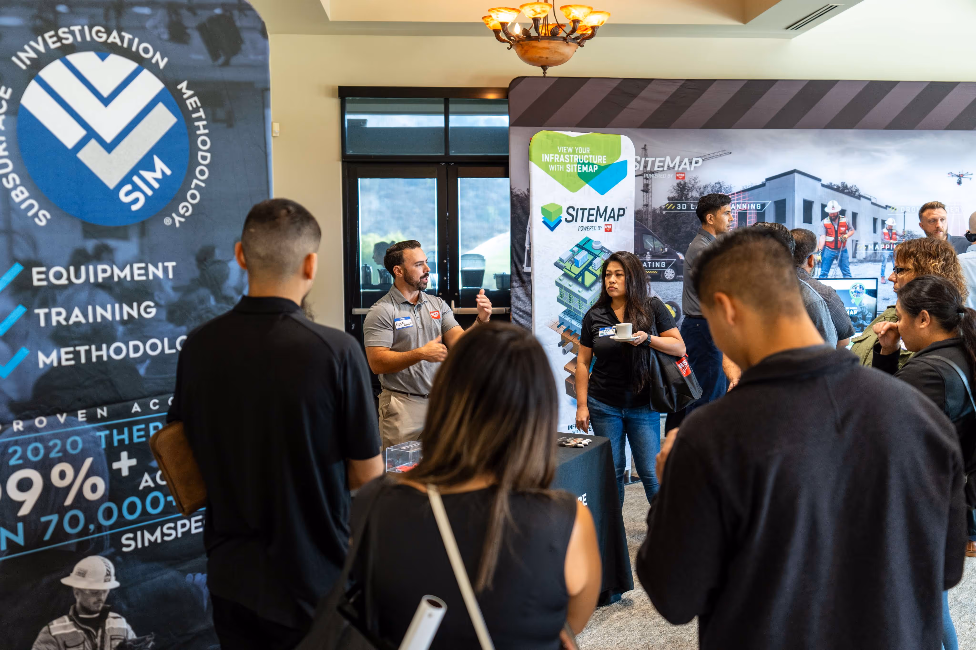 A presenter in SITEMAP apparel speaks at a GPRS Construction Tech Day demonstration, highlighting tools for safer site management and damage prevention.