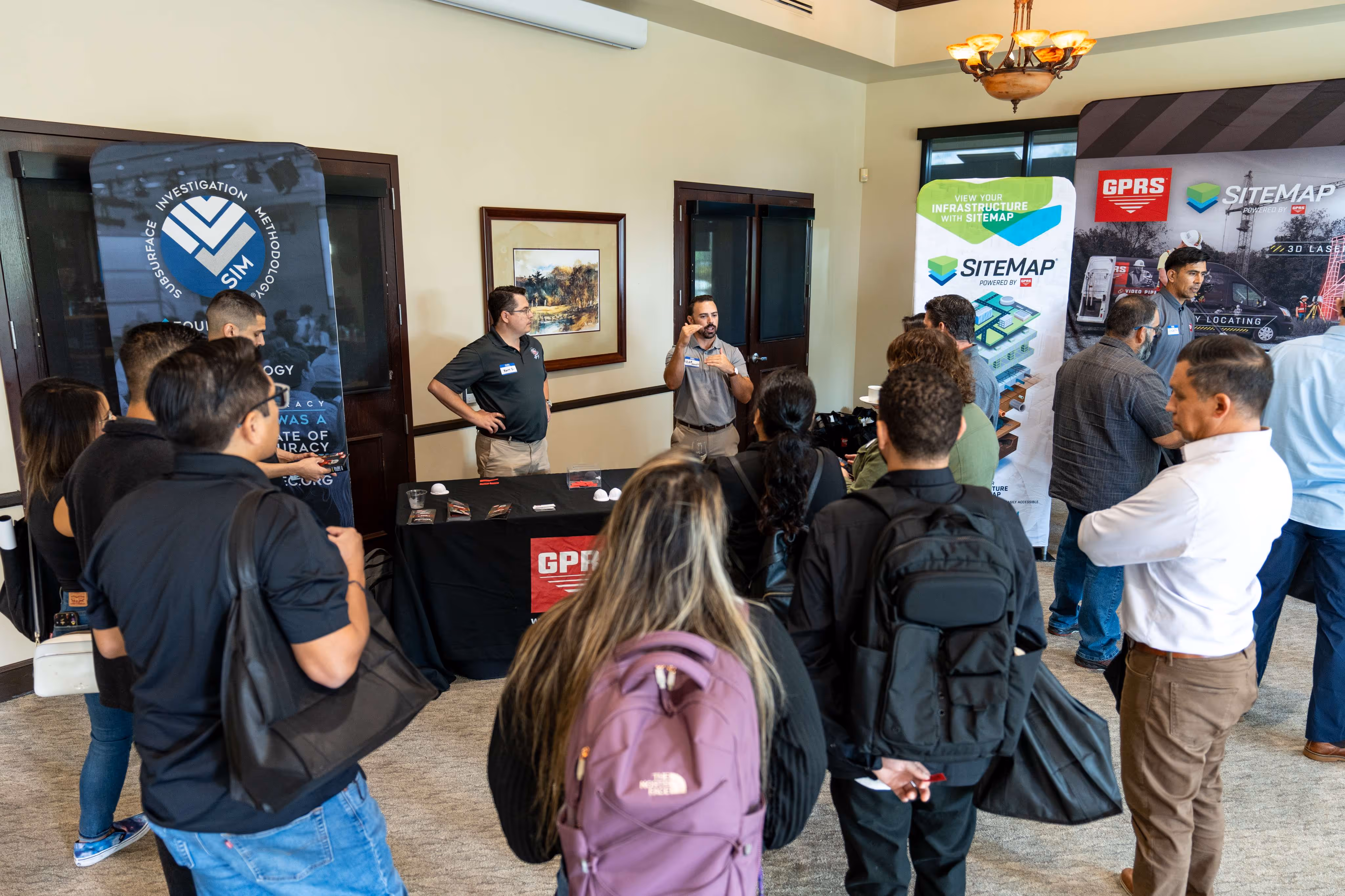 Attendees gather around a GPRS booth during Construction Tech Day as presenters explain SITEMAP technology, damage‑prevention tools, and site‑planning solutions.