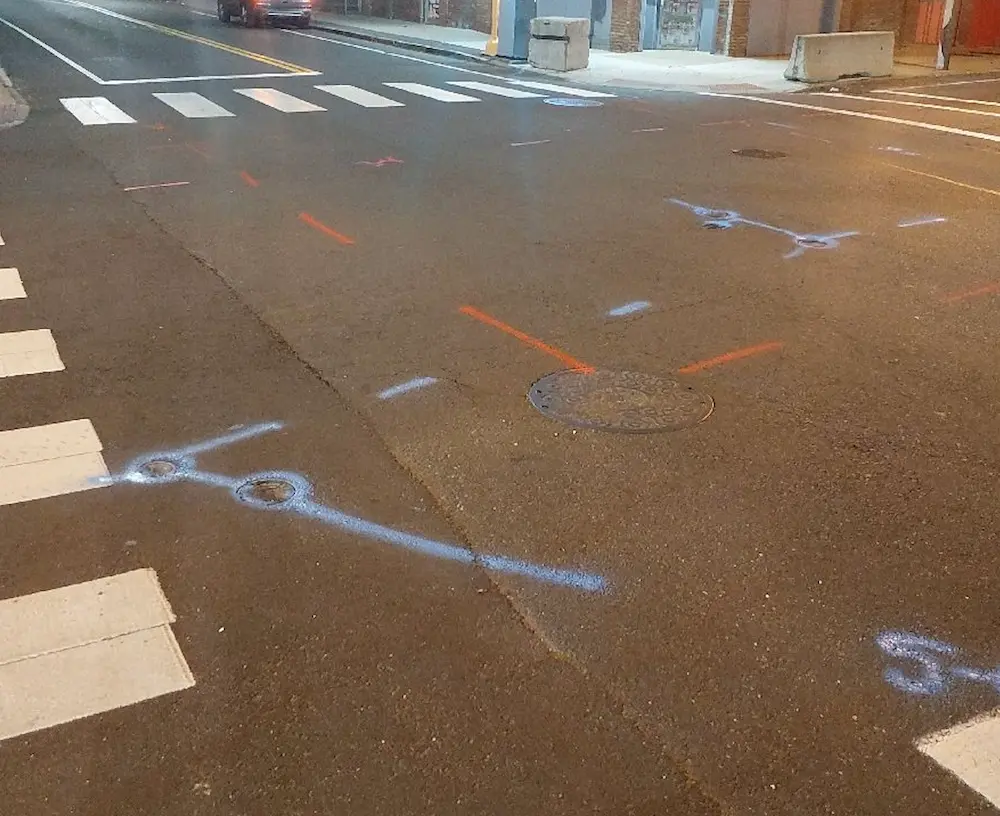 A street featuring utility markings and a crosswalk, with spray paint indicating underground utilities by GPRS.