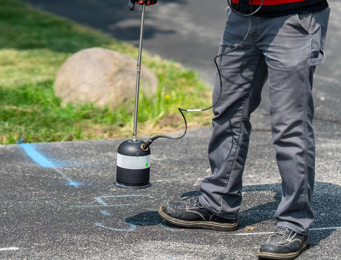 A man stands on a worksite, holding an acoustic leak detector, overseeing the GPRS project.