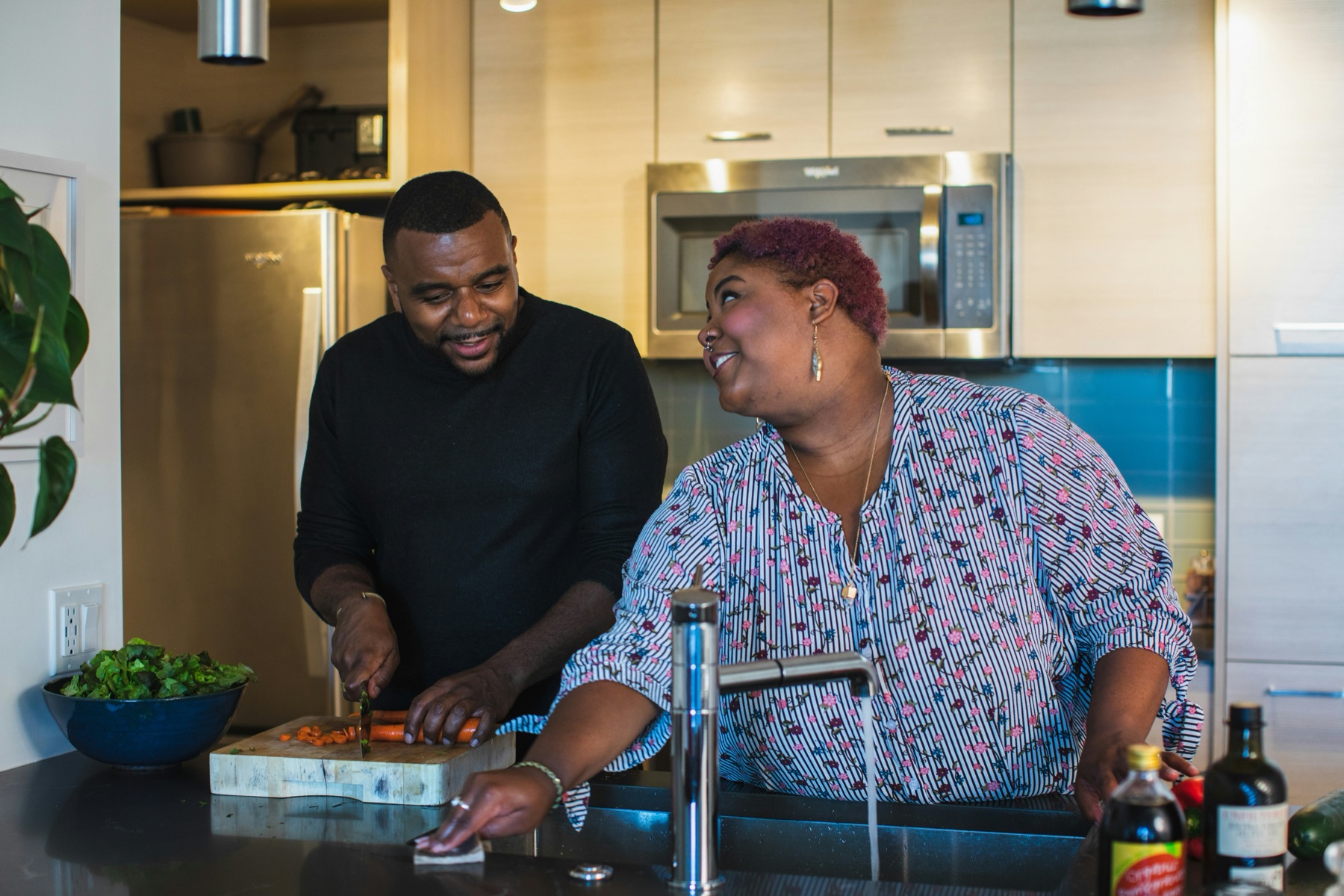 An older Black couple cooking a healthy meal together at home