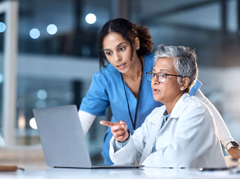 Healthcare staff assisting an older patient on a laptop, representing referral and patient intake marketing materials created through Veewz healthcare marketing services.