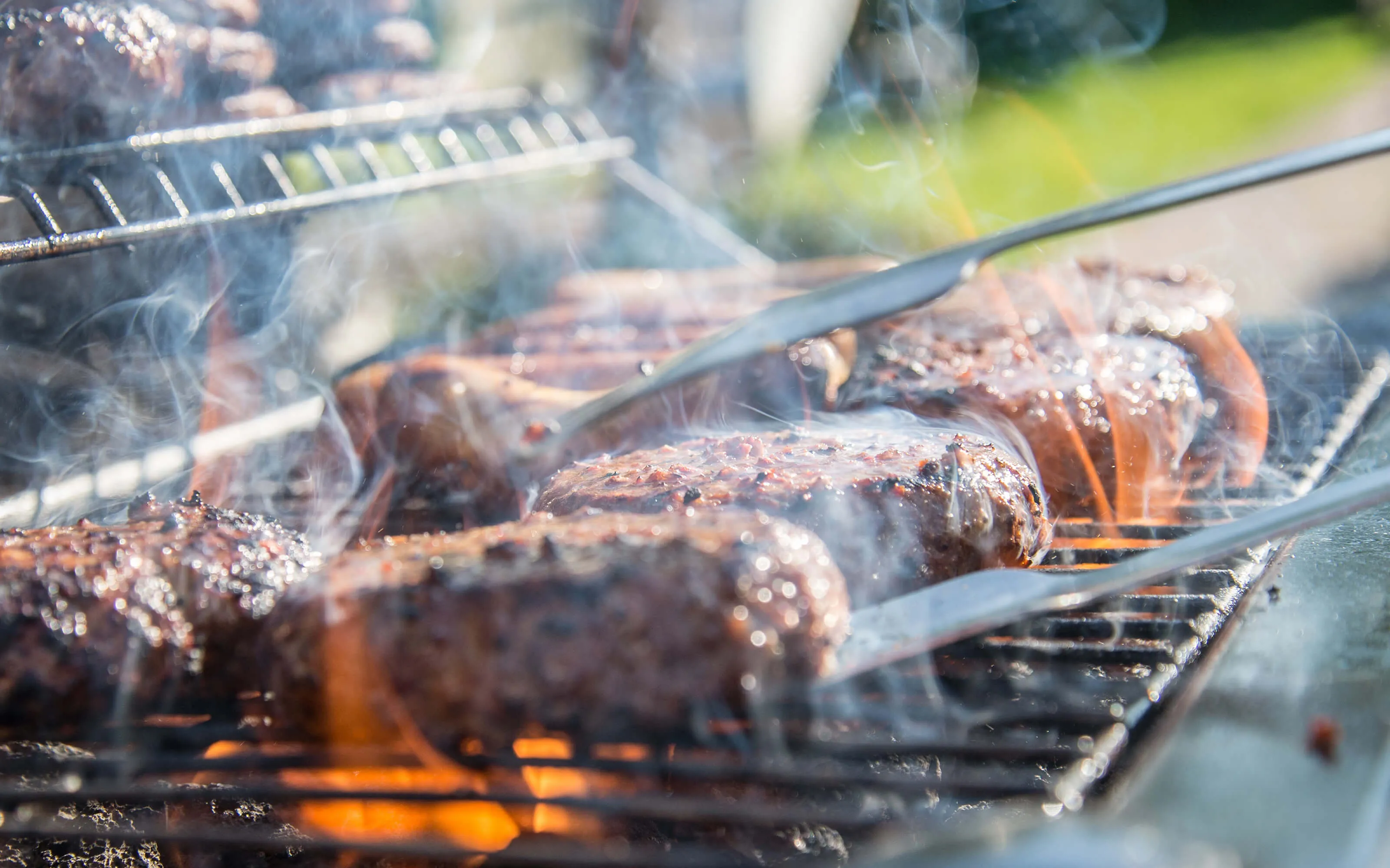 Sausages, steaks and burgers cooking on a BBQ