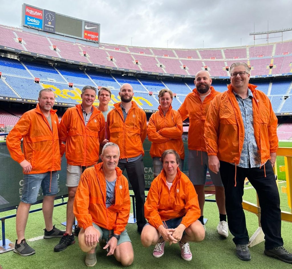 Testersuite Team in orange jackets posing at Camp Nou in Barcelona