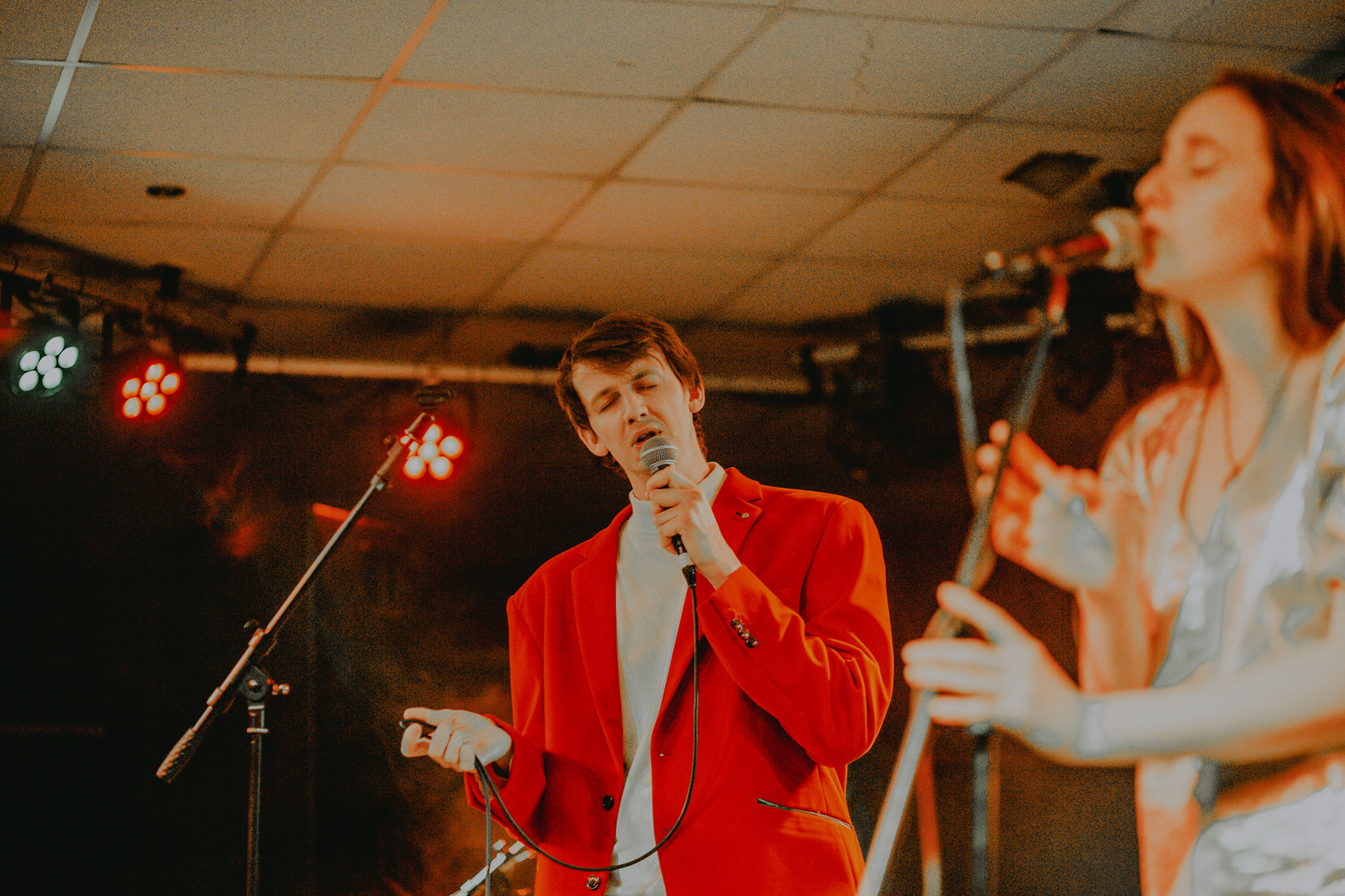 A man sings passionately at the front of the stage