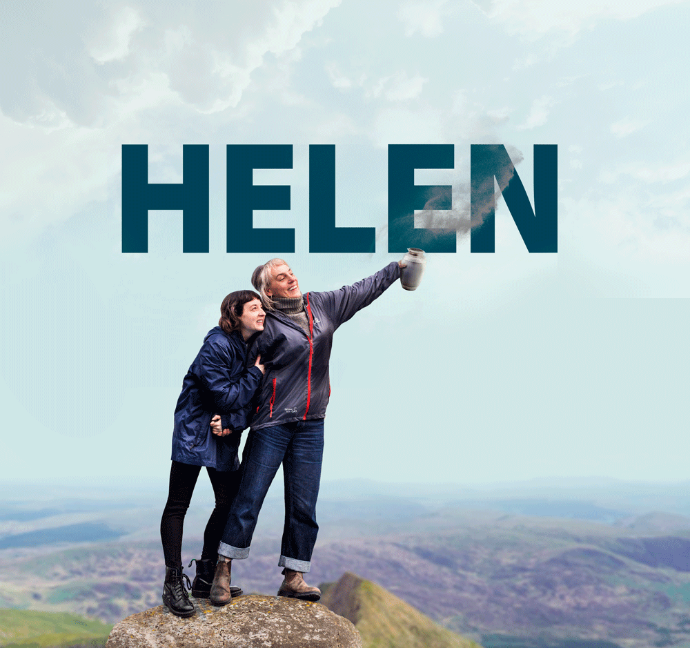 A mother and daughter release ashes at the top of a mountain with smiles on their faces. The words "HELEN" are being them.