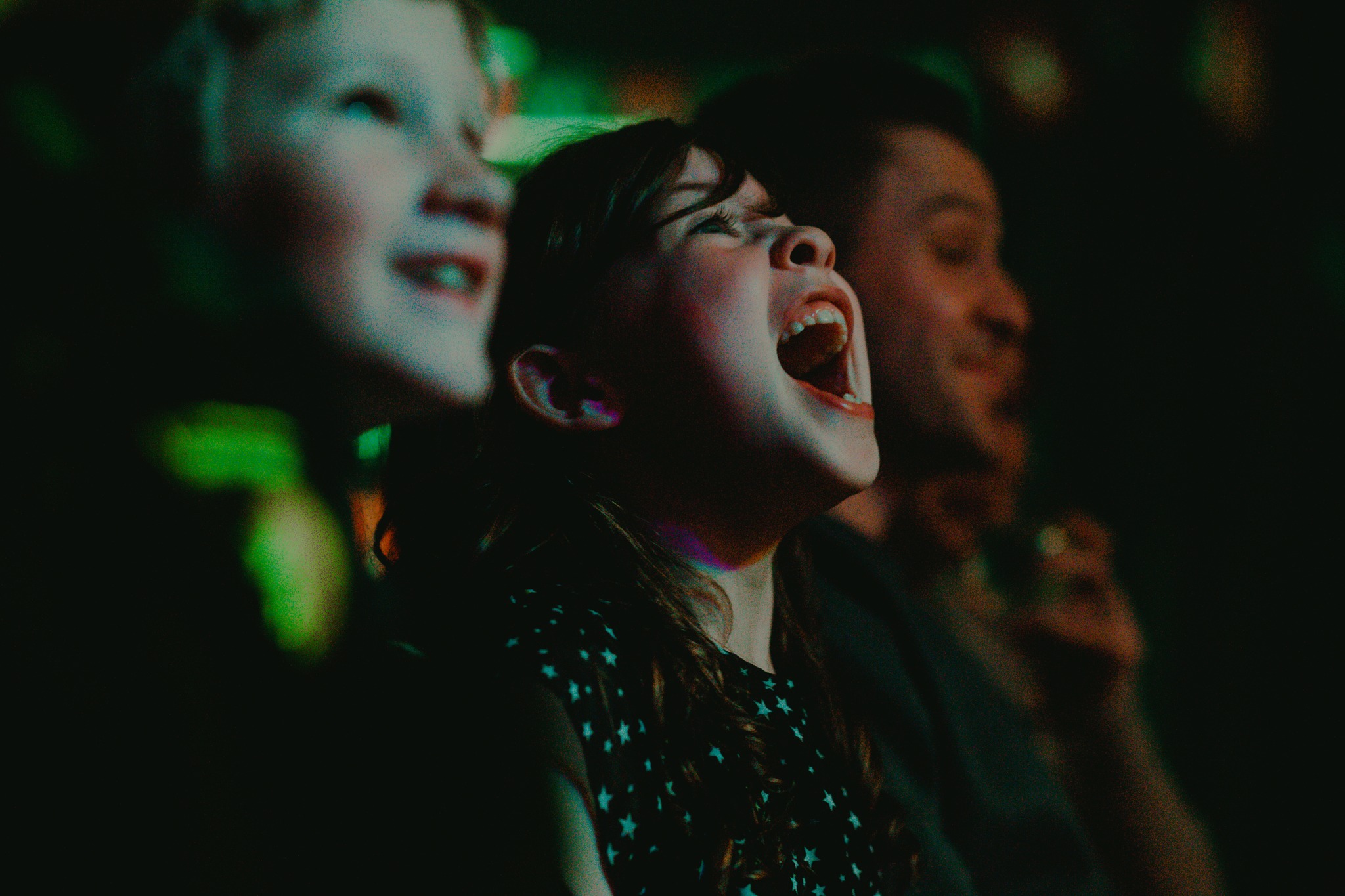 A child gleefully laughs at the stage at the front of an audience