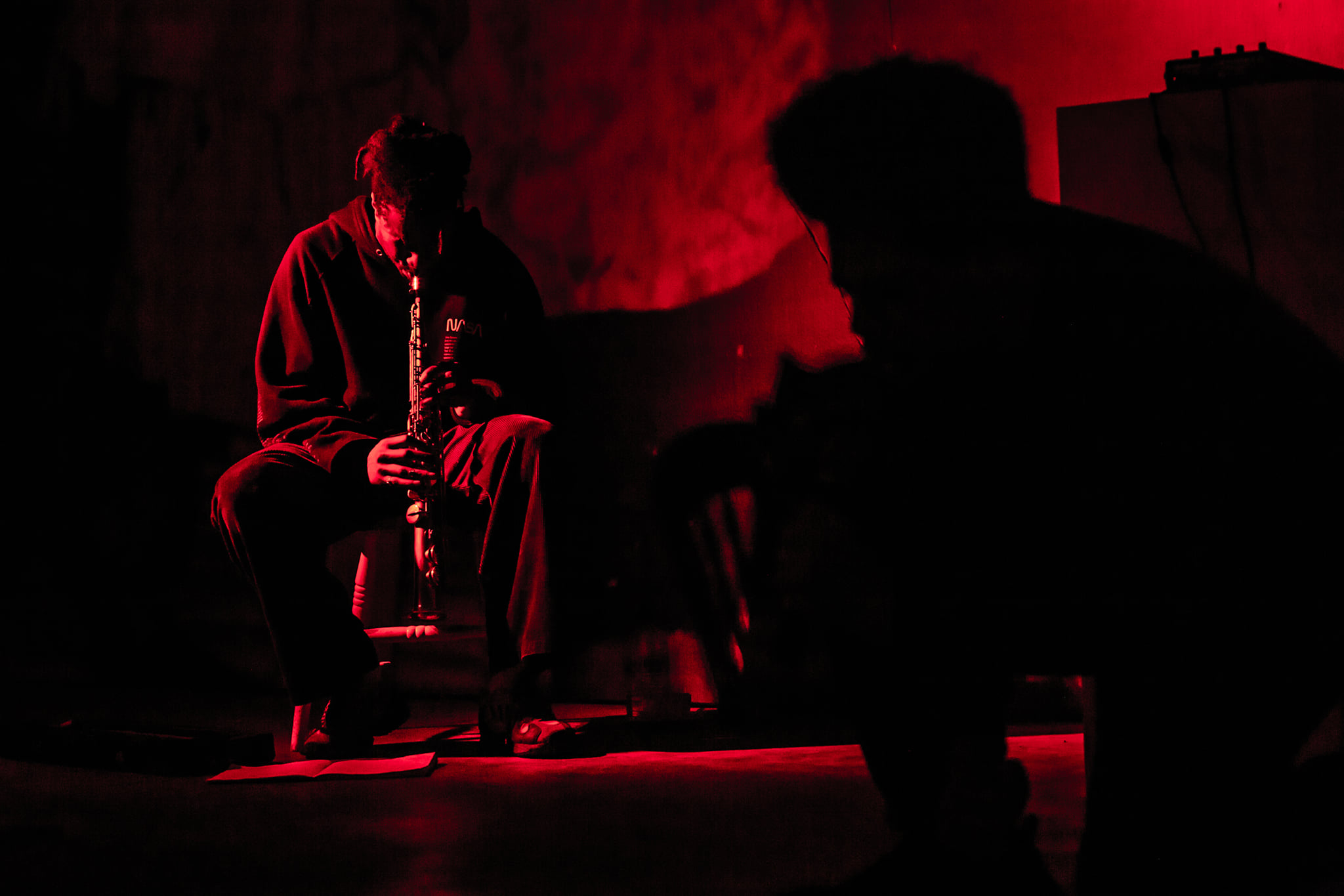 Two men perform in red lighting