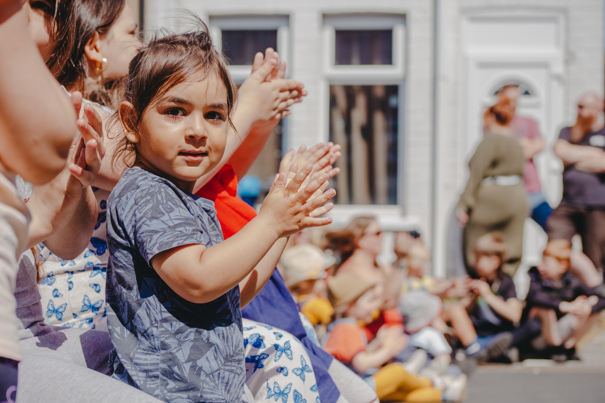 An audience claps as a small girl looks towards the camera