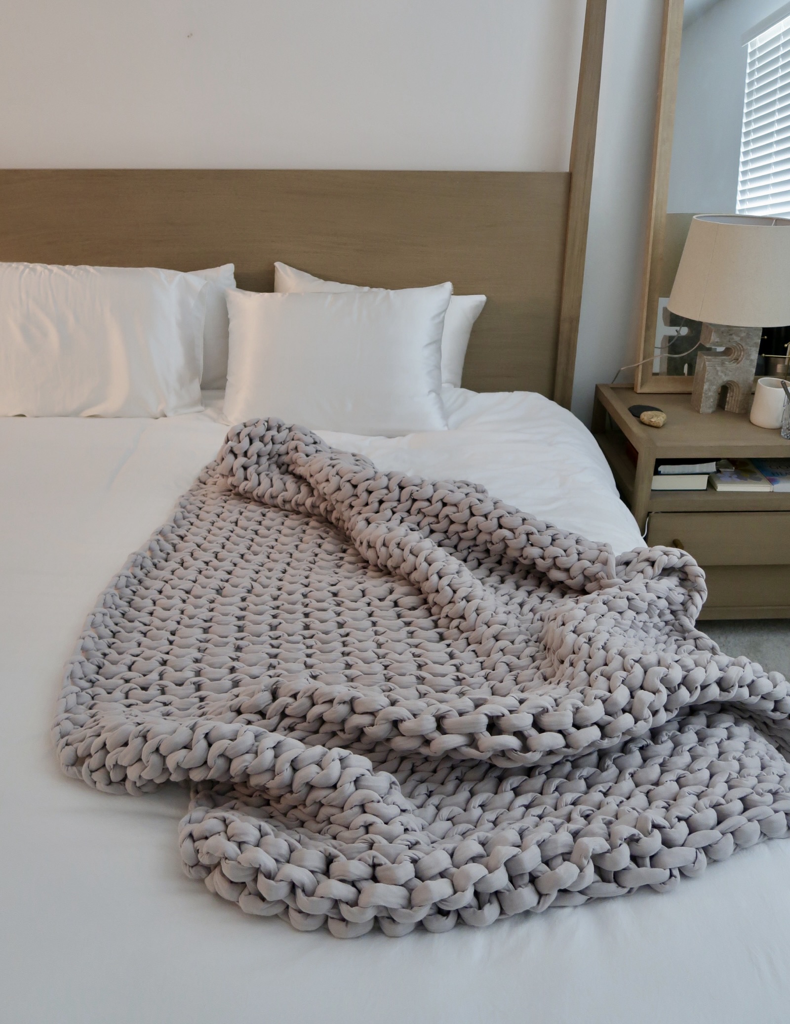 Bearaby Cotton Napper weighted blanket in gray draped elegantly over a modern bed