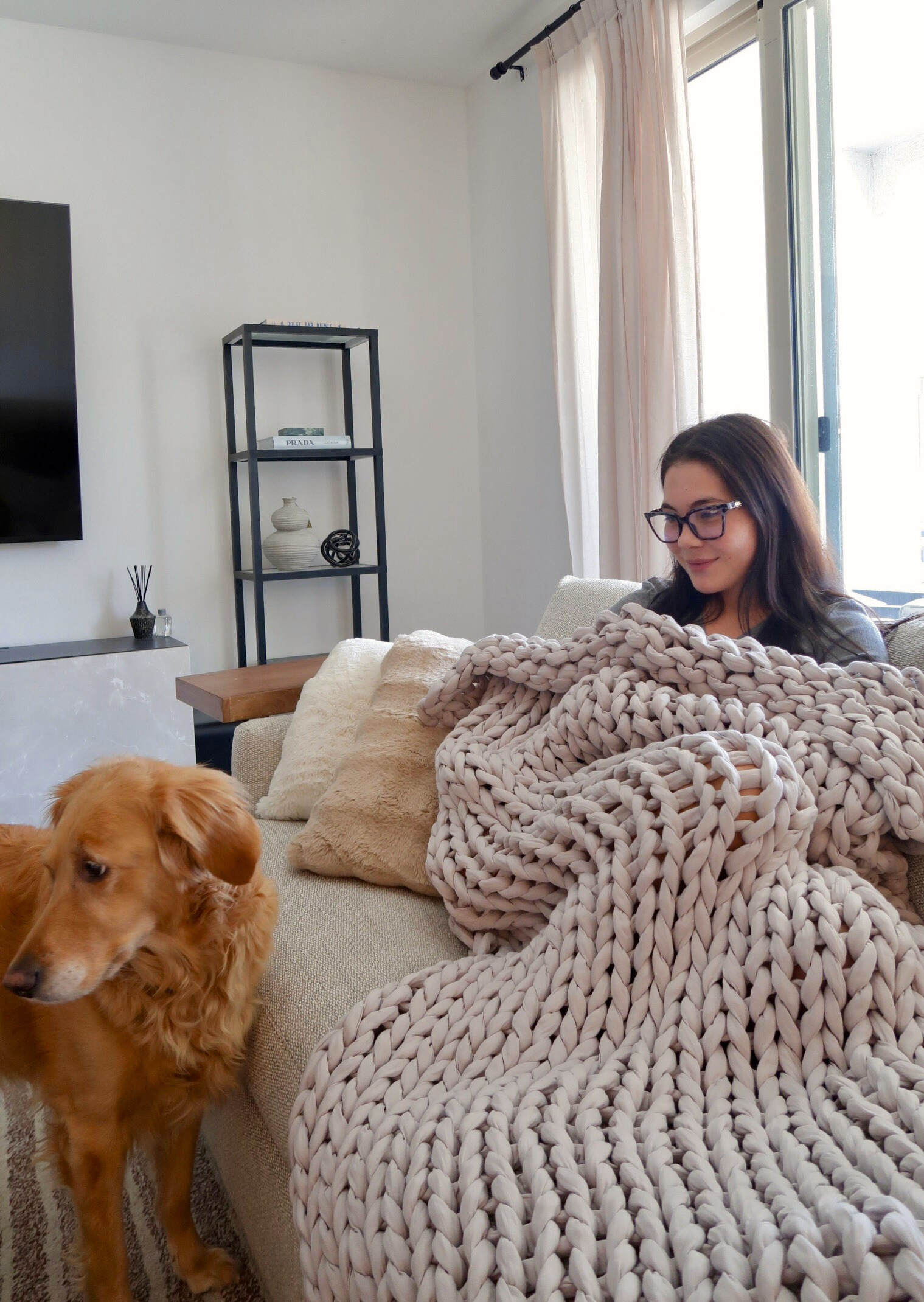 Person relaxing at home wrapped in the Bearaby Cotton Napper weighted blanket.