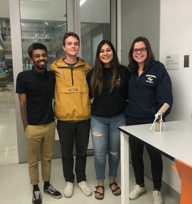 Students standing together for a group photo in their workspace