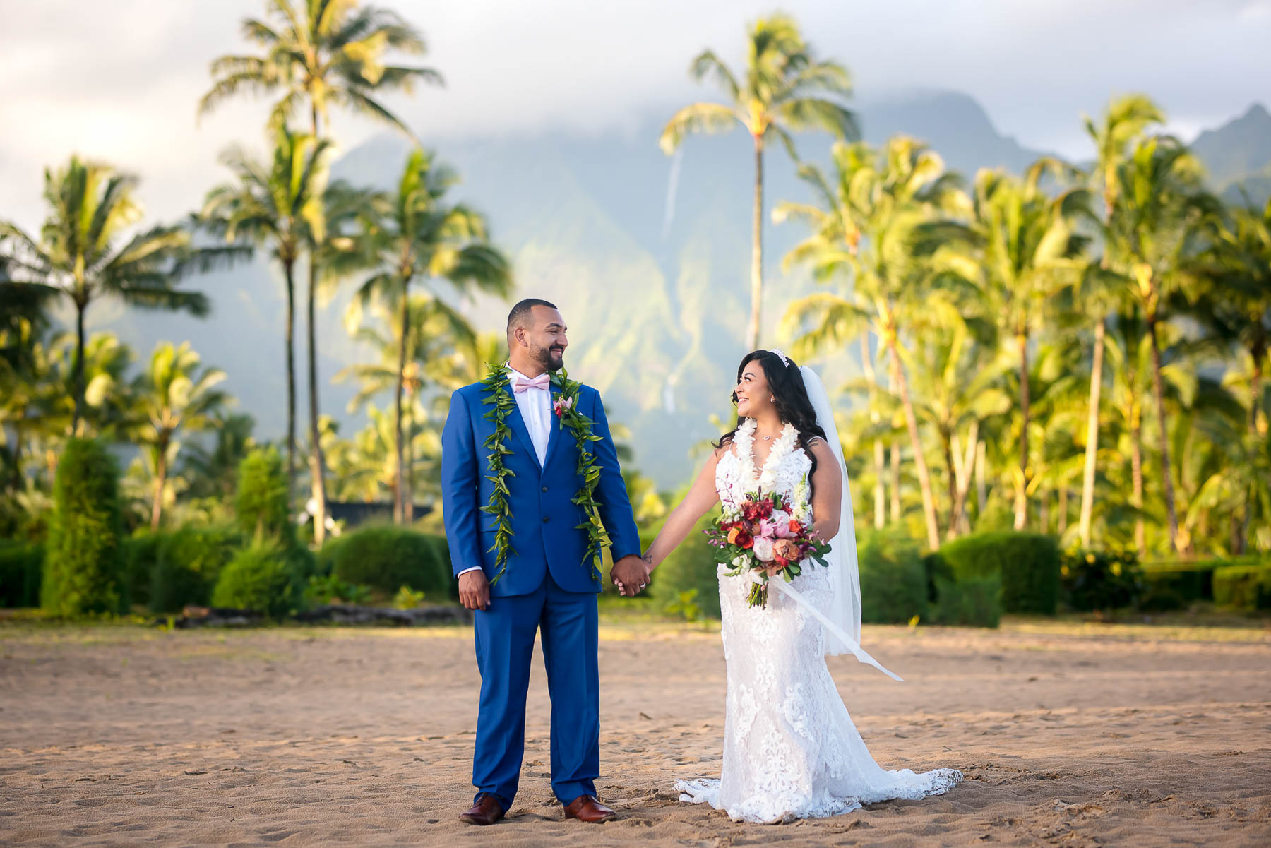 Hawaii elopement wedding bride and groom holding hands in front of palm trees  and waterfall in mountains