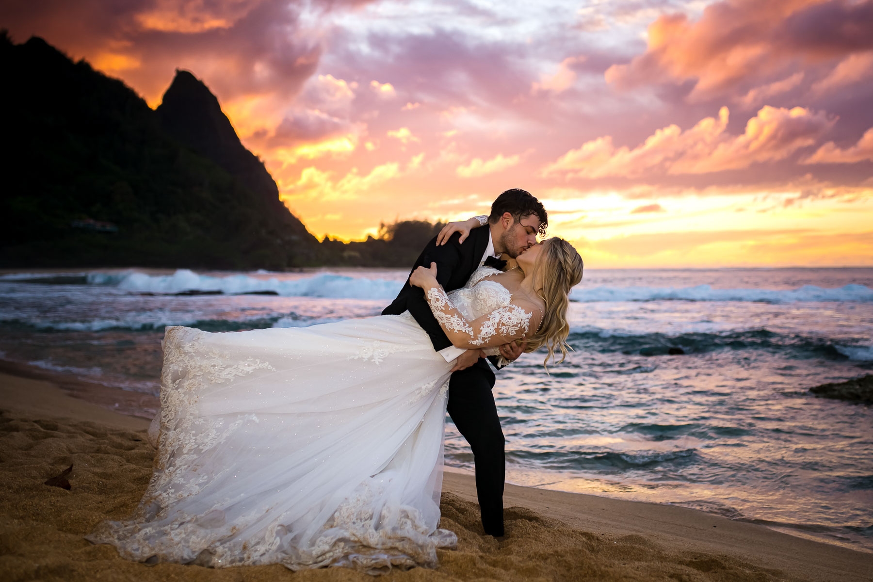 couple kissing at sunset on beach in Hawaii after getting married