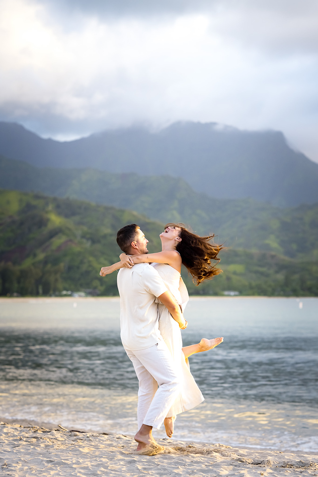 couple embraces after surprise proposal and engagement in Hanalei bay kauai