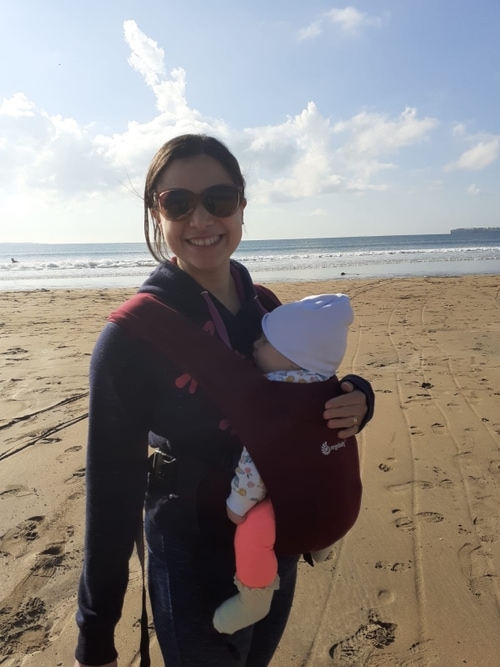 A woman holding a baby on a beach.