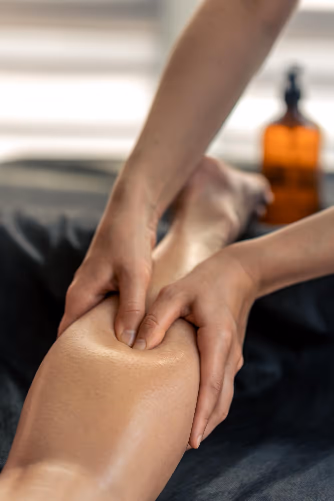 Close-up of hands performing deep tissue massage on a person's lower leg.