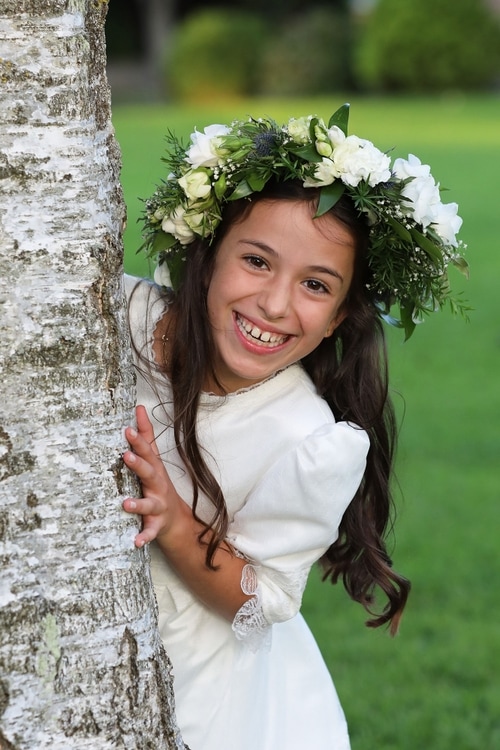 Communion girl peeping around tree by Jenny Callanan Photography