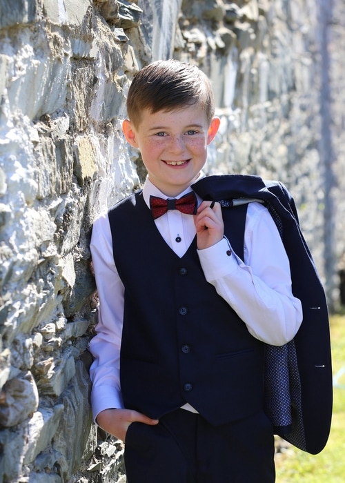 Communion boy leaning on a wall by Jenny Callanan Photography