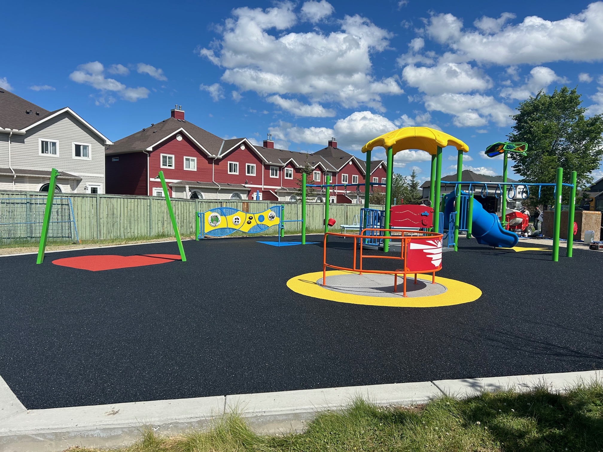 Bayside Rise inclusive playground in Airdrie with accessible merry-go-round, slides, and sensory play panels